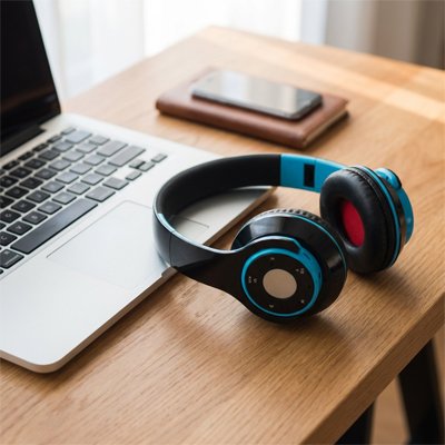 Casque audio Bluetooth posé sur un bureau près d’un ordinateur portable
