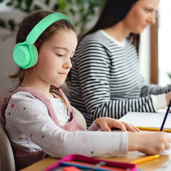 Enfant portant un casque audio sans fil vert pendant une activité à table
