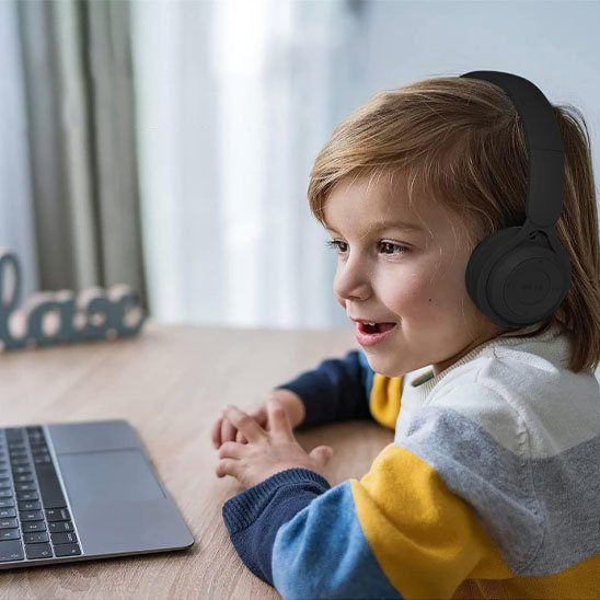 Enfant utilisant un casque audio sans fil devant un ordinateur portable
