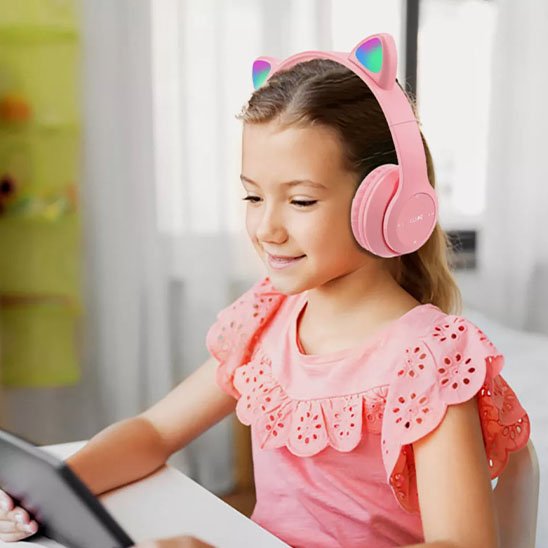 Fillette avec casque Bluetooth rose sur tablette