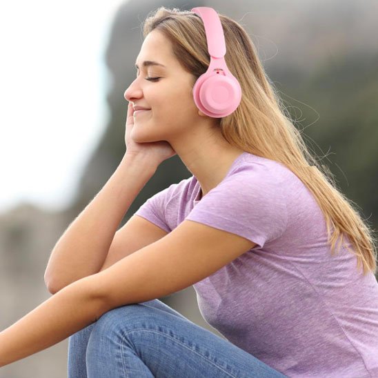 Jeune fille portant un casque Bluetooth rose assise en extérieur